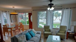 A living room with a sofa, armchairs, a coffee table, and a dining area with chairs and a table. - Casa Playasol (Puerto Morelos)