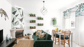 Un salon moderne avec une cheminée, un canapé vert, une table à manger en bois et des plantes en pot.