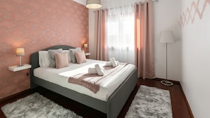 Une chambre à coucher bien rangée, avec un lit, des lampes de chevet et une lampe sur pied.