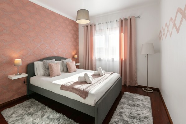 Un dormitorio ordenado con cama, lámparas de noche y una lámpara de pie.