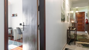 Un couloir avec une porte en bois, un bureau avec une chaise et un tapis.