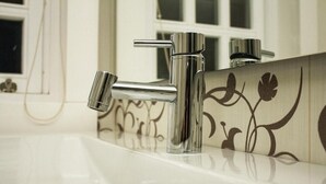 Une salle de bain dotée d’un robinet moderne et d’un panneau mural décoratif.
