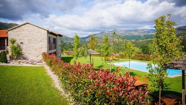 Un bâtiment en pierre doté d’une piscine et d’un jardin bien entretenu.