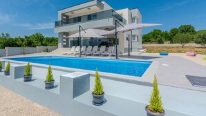 A modern two-story house with a swimming pool, sun loungers, and potted plants. - Awesome home in Slivnica Donja (Slivnica Donja)
