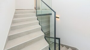 A modern staircase with glass railings and a light fixture on the wall. - Awesome home in Slivnica Donja (Slivnica Donja)