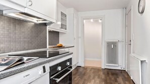 Une cuisine moderne équipée d’une cuisinière Bosch, de meubles blancs et d’un revêtement mural en carreaux.
