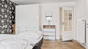 Une chambre à coucher comprenant un lit, une commode, une coiffeuse avec un miroir et une armoire.