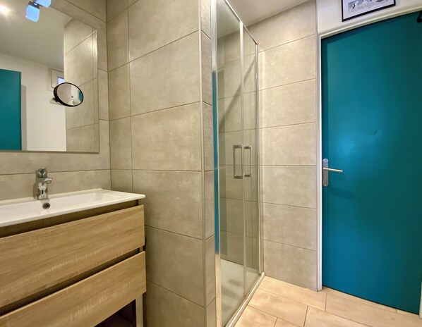 A bathroom with a sink, mirror, and glass shower enclosure.