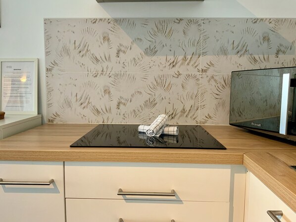 A modern kitchen with a black countertop, a white cabinet, and a patterned backsplash.