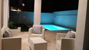 An outdoor seating area with wicker furniture and a pool. - Beautiful Villa in Cabarete Puerto Plata .walking Distance to the beach . (Cabarete)