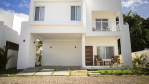 A modern two-story house with a flat roof, a covered garage, and a balcony on the upper floor. - Beautiful Villa in Cabarete Puerto Plata .walking Distance to the beach . (Cabarete)