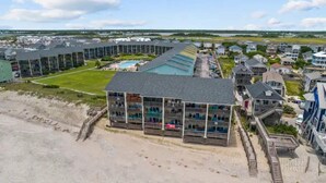 A coastal hotel with multiple balconies, a swimming pool, and a beach access. - Gorgeous Beachfront Condo with Pool (Surf City)