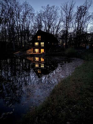 Overlooking the serene lake, this house features a spacious balcony and a warm, inviting glow.