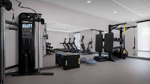 A modern gym with various exercise equipment, including a weight machine, treadmills, and a squat rack. - Home2 Suites By Hilton Chattanooga East Ridge (Chattanooga)