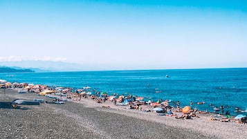 Plage à proximité, sable noir, chaises longues, parasols