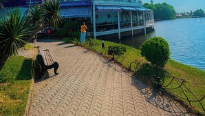 Una passeggiata lungo il fiume con una panchina, un edificio con tenda blu e vista su un moderno grattacielo sullo sfondo.