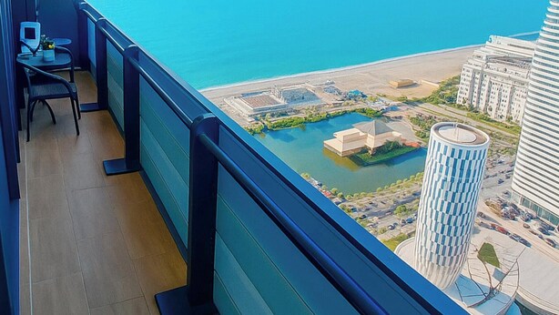 Un balcone con vista sulla spiaggia e su edifici moderni.