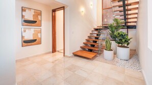 A modern interior with a wooden staircase, two framed abstract paintings, and potted plants.