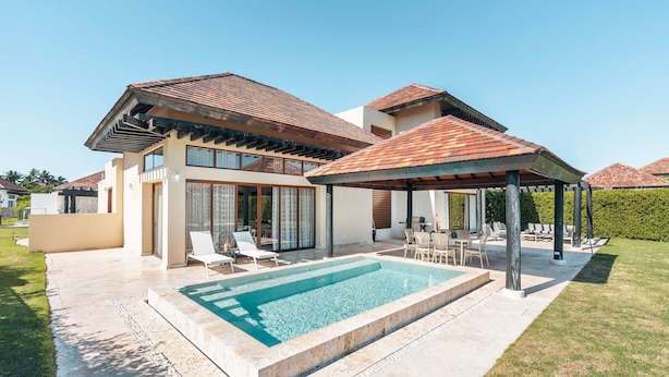 A modern house with a swimming pool, outdoor seating, and a covered patio.