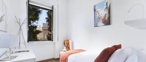 Un dormitorio moderno con cama, escritorio, ventana y un cuadro en la pared.
