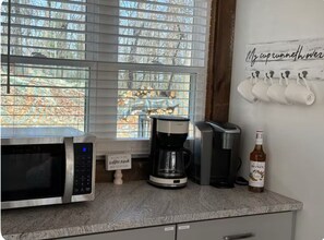 A kitchen with a microwave, coffee maker, and a bottle of Monin syrup on the counter. - Relax near Gettysburg ski/wineries/fire pit! (Orrtanna)