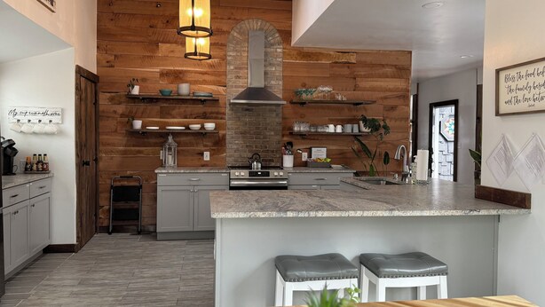 Una cucina moderna con elementi in legno, un'isola centrale e sgabelli da bar.