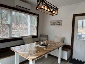A modern kitchen with a large wooden herringbone table, a built-in bench, and a hanging light fixture. - Relax near Gettysburg ski/wineries/fire pit! (Orrtanna)