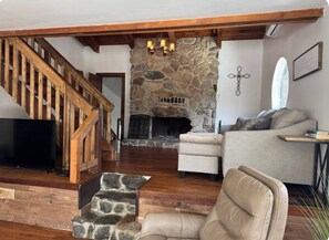 A living room with a stone fireplace, wooden staircase, and a television. - Relax near Gettysburg ski/wineries/fire pit! (Orrtanna)