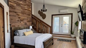 Una camera da letto con un letto in legno, una scala, un lampadario, una pianta in vaso e un televisore montato a parete.