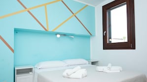Une chambre à coucher avec un lit, des oreillers blancs, une table de chevet, une commode et une fenêtre donnant sur un beau paysage.