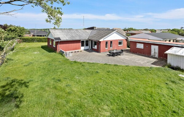 A red building with a covered patio and a grassy yard. - Lovely home in Vestervig with kitchen (Vestervig)