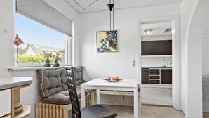 Une cuisine compacte comprenant un coin repas, un radiateur et une fenêtre donnant sur un espace verdoyant.