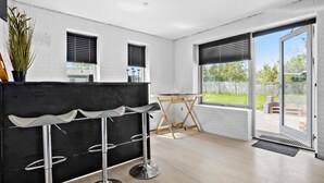 Une cuisine moderne avec un plan de travail noir, des tabourets de bar blancs et une table en bois.