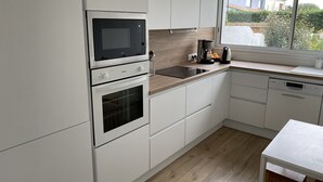 A modern kitchen with white cabinetry, a built-in oven, a microwave, and a coffee maker.