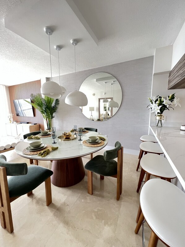 A modern dining area with a round table, chairs, and pendant lights. - Chic Penthouse  in the heart of Miami amazing Ocean and Sunset view (Miami)