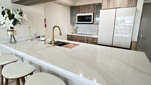 A modern kitchen with a marble countertop, stainless steel appliances, and wooden accents. - Chic Penthouse  in the heart of Miami amazing Ocean and Sunset view (Miami)