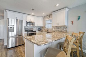 Una cocina moderna con gabinetes blancos, electrodomésticos de acero inoxidable y encimera de granito.