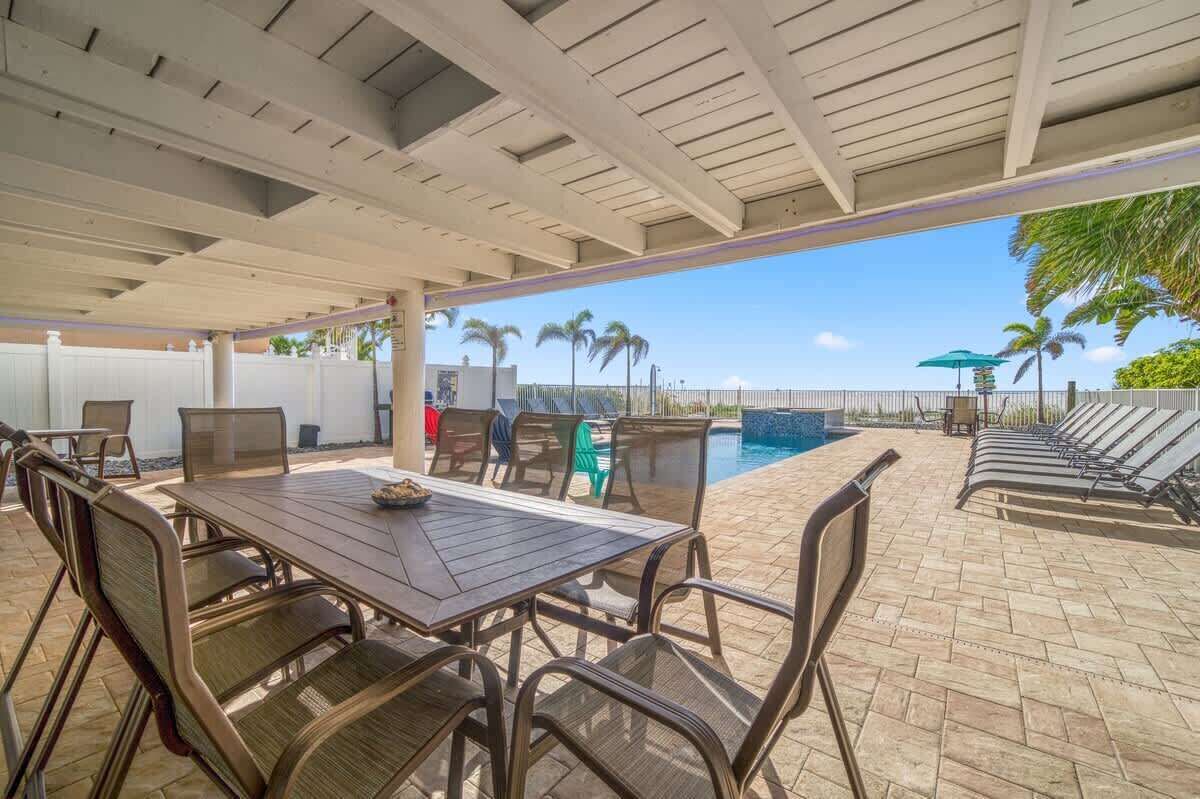 An outdoor patio area with a pool, lounge chairs, and a table with chairs.