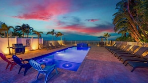 An outdoor pool area with lounge chairs and a barbecue grill.