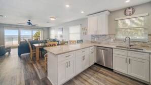 A modern kitchen with a large island, white cabinetry, and a view to the outside.
