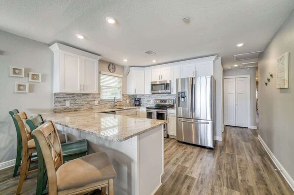 A modern kitchen with white cabinets, stainless steel appliances, and a central island with seating.