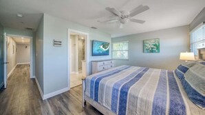 A bedroom with a bed, a ceiling fan, a door, and a window.