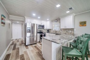 A kitchen with white cabinets, a granite countertop, and a built-in island with bar stools.