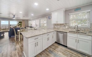 A spacious kitchen with white cabinetry, a large island, and a view of the ocean.