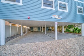 A blue building with a covered parking area, a sign indicating a pet-friendly establishment, and a gravel driveway. - 2000 SqFt Condo with Private Indoor Poolside Cabana (Indian Shores)