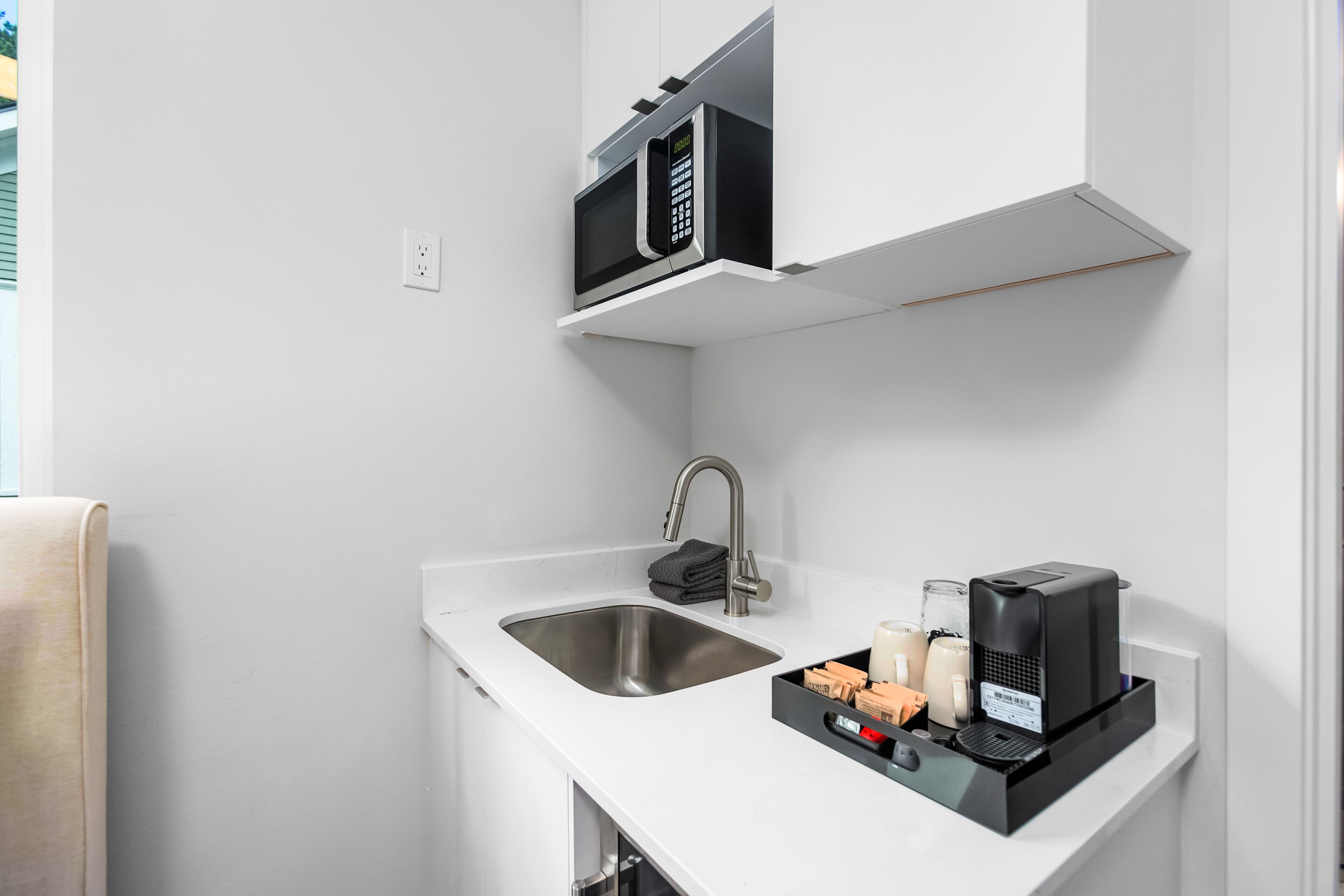 A modern kitchen with a built-in microwave, a stainless steel sink, and a coffee maker.
