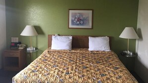 A hotel room with a bed, two bedside lamps, a nightstand, and a framed picture on the wall. - Prairie Rose inn   (Edgeley)