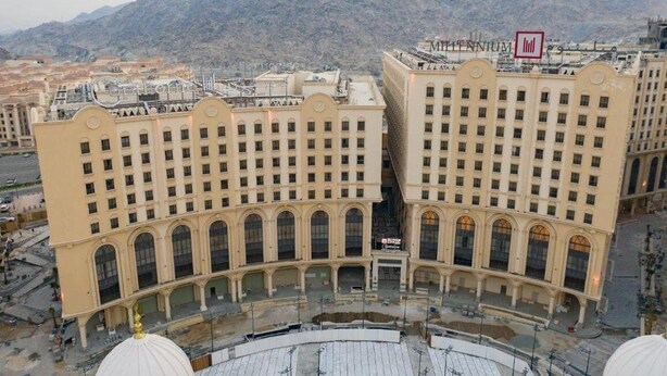 A large, beige building with multiple floors and arched windows, surrounded by mountains. - Copthorne Makkah Al Naseem (Makkah)