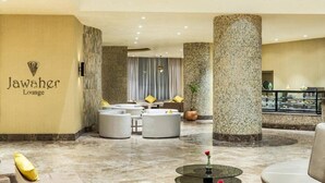A Jawaher's lounge with a modern design, featuring a marble floor, comfortable seating, and a large pillar. - Copthorne Makkah Al Naseem (Makkah)