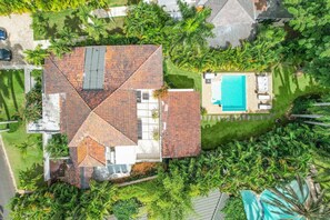 A house with a tiled roof, a swimming pool, and lush greenery. - Caralva 172: Tranquil villa w/ pool, lush garden, housekeeper, and golf cart (Casa de Campo)
